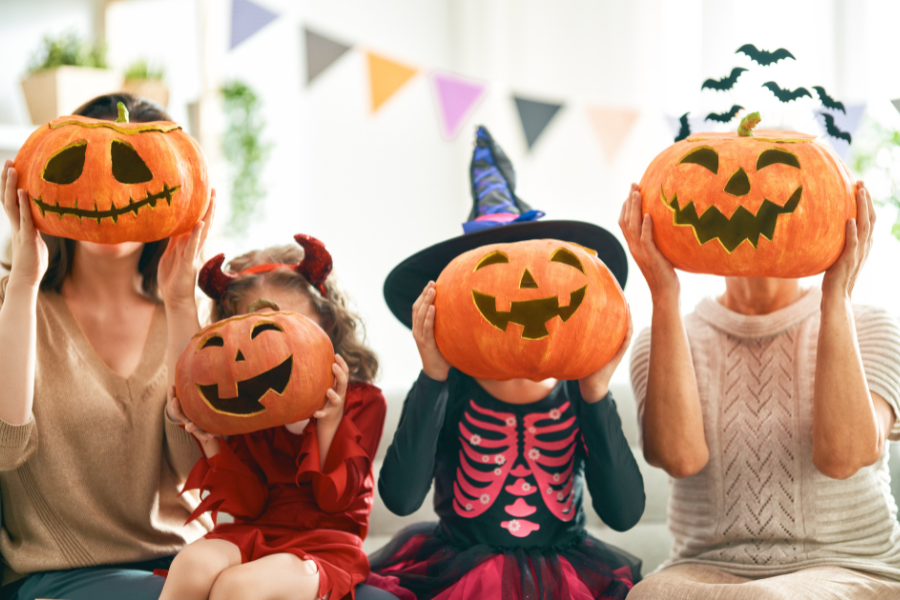 Kids in Halloween costumes, holding up pumpkins