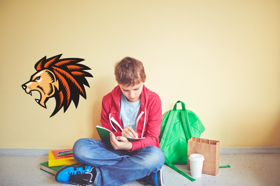 Boy sitting on floor writing in his work book.