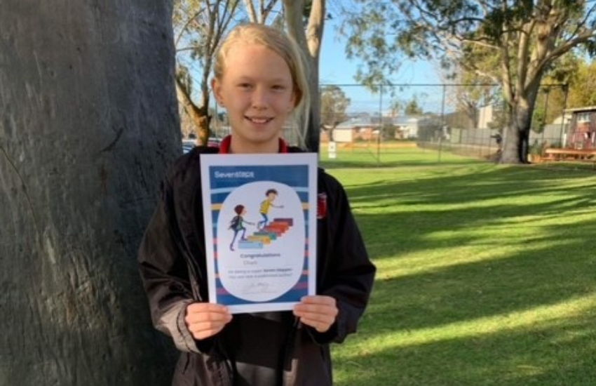Year 5 student holding her informative writing certificate